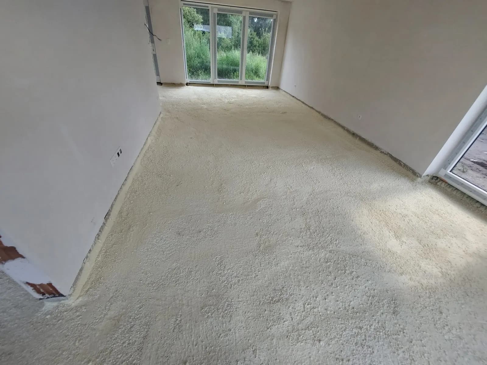 Kamer in een nieuwbouwwoning met afgewerkte gespoten PUR-vloerisolatie, strak aangesloten tegen de muren